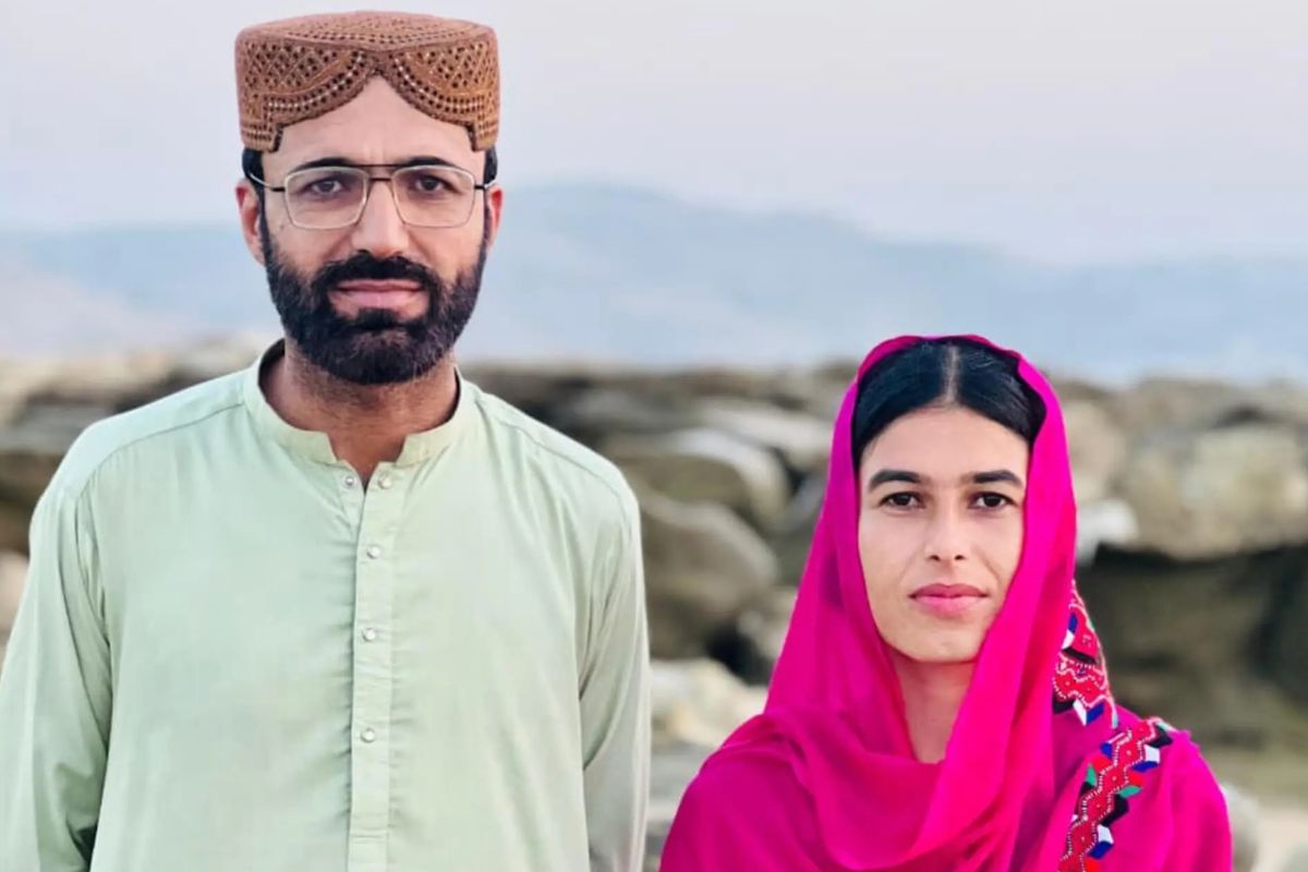 Das Foto zeigt Dad Shah und Fozia Baloc nebeneinander in einer Landschaft stehen und leicht in die Kamera lächelnd. Sie tragen traditionelle Kleidung.