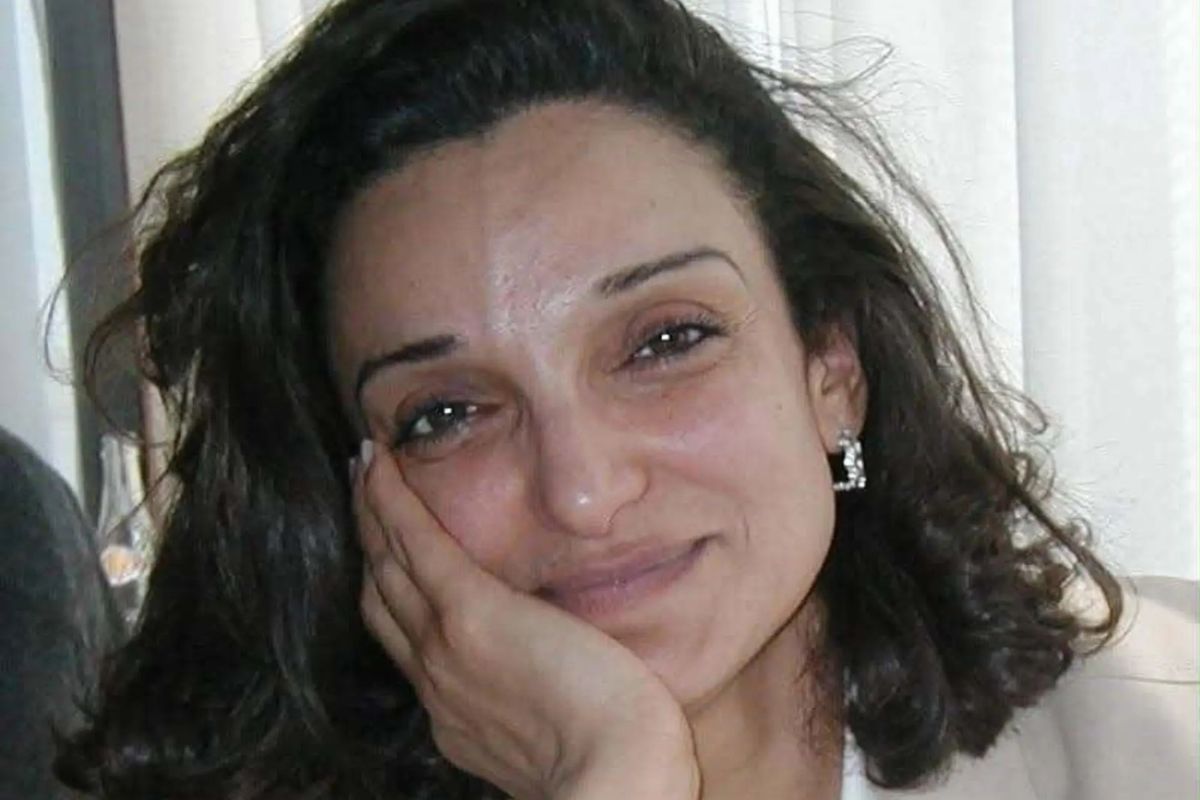 Porträtfoto von Saloua Ghrissa, die ihren Kopf mit ihrer rechten Hand stützt und in die Kamera lächelt.
