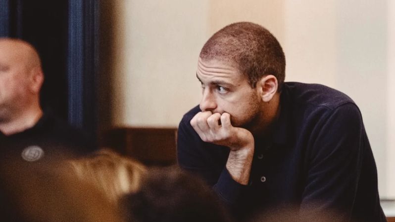 Ein Mann mit kurzen Haaren, Kinn auf die Hand gestützt, schaut angestrengt