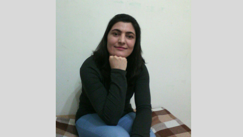 Porträtfoto von Zeynab Jalalian, die ihr Kinn auf ihre rechte geschlossene Hand stützt und ernst in die Kamera blickt.