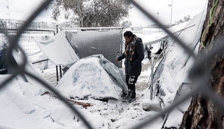 Ein Flüchtling vor einem schneebedeckten Zelt auf der griechischen Insel Lesbos im Januar 2017