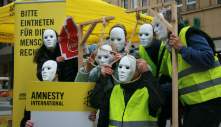 Menschen mit weißen Masken imitieren die Todesstrafe mit Galgen