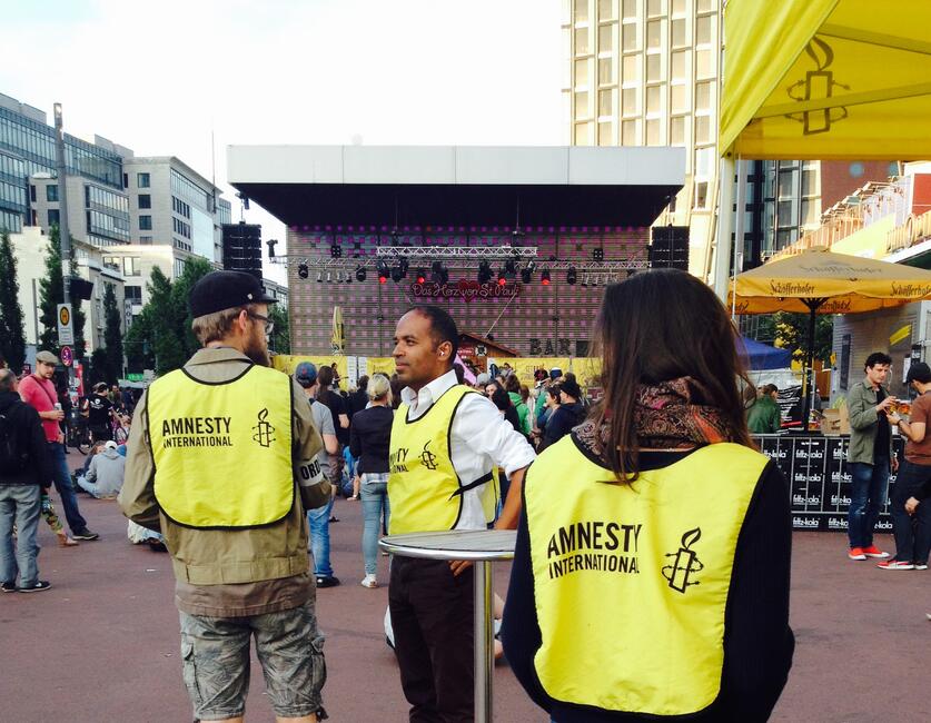 Markus N. Beeko mit Amnesty Aktivisten auf einem öffentlichen Platz mit einer Bühne in Hamburg 