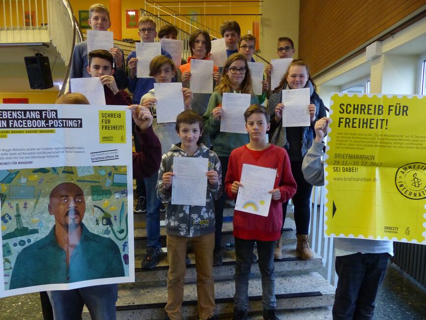 Schülerinnen und Schüler stehen auf auf einer Treppe, zwei Plakate zum Briefmarathon 2017 werden hochgehalten