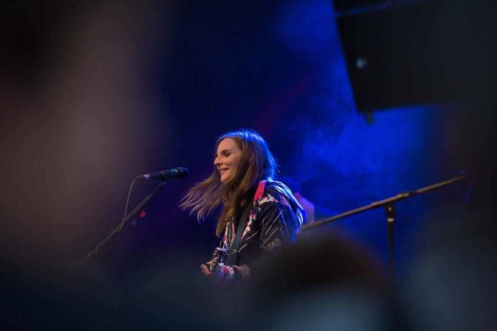 Eine junge Musikerin mit wehendem langen Haar singt beschwingt ins Mikrofon