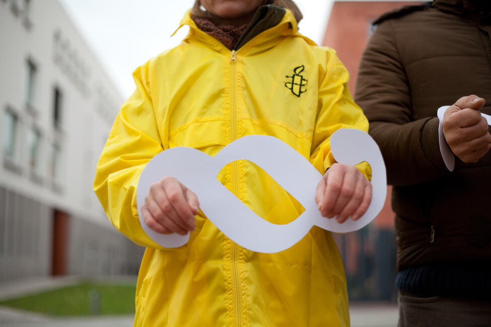 Eine Person hält einen Paragraphen Symbol aus Papier als Handschellen hoch