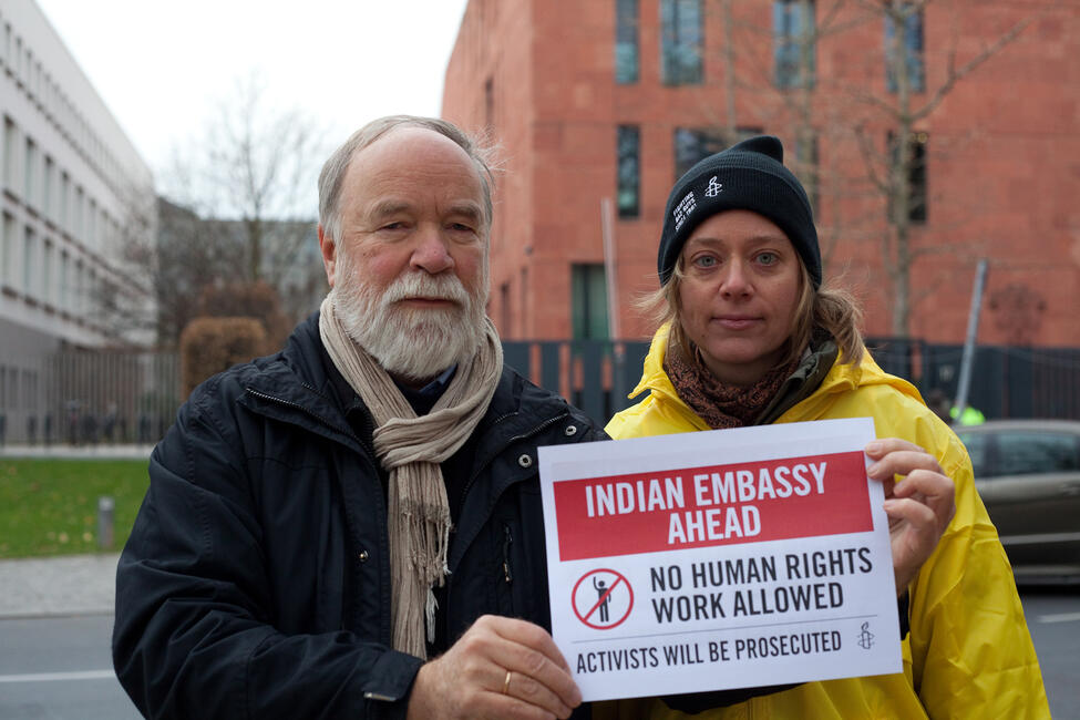Zwei Personen halten ein Schild hoch