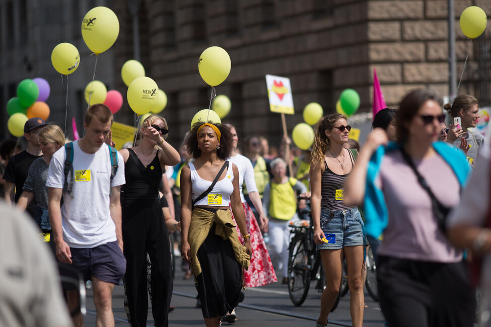 Viele Menschen demonstrieren mit Schildern, Lufballons und Fahnen auf einer Straße
