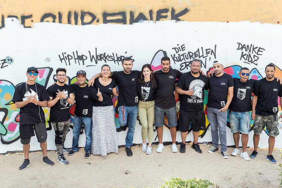 Eine Gruppe von Männern und Frauen aufgereiht vor einer Hauswand