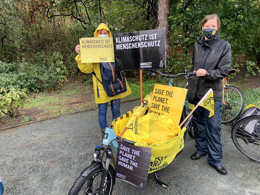 Amnesty-Aktive bei der Klimademo, sie schieben ein Lastenrad in dem Amnesty-Flyer und Plakate liegen