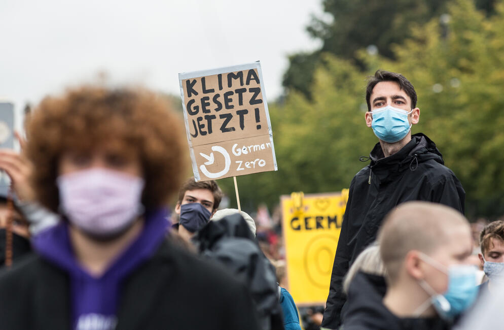 Verschiedene Menschen auf der Klima-Demo, wegen Corona mit Maske, sie tragen Schilder wie "Klima Gesetz jetzt"!