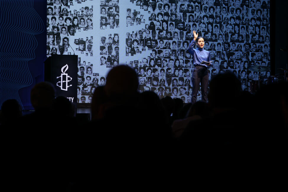 Das Bild zeigt eine Person auf einer Bühne, im Vordergrund das Publikum