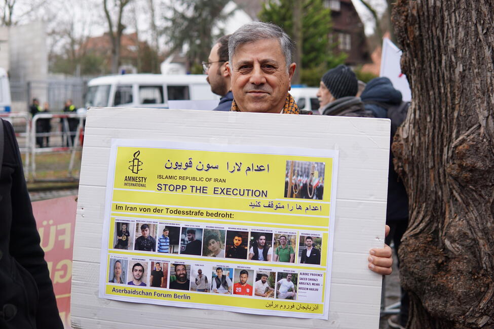 Das Bild zeigt einen Mann mit einem Protestplakat