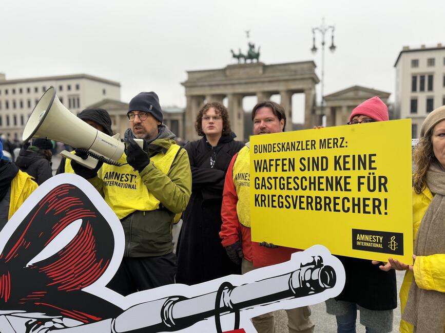 Mehrere Menschen protestieren mit Plakaten und Megaphon