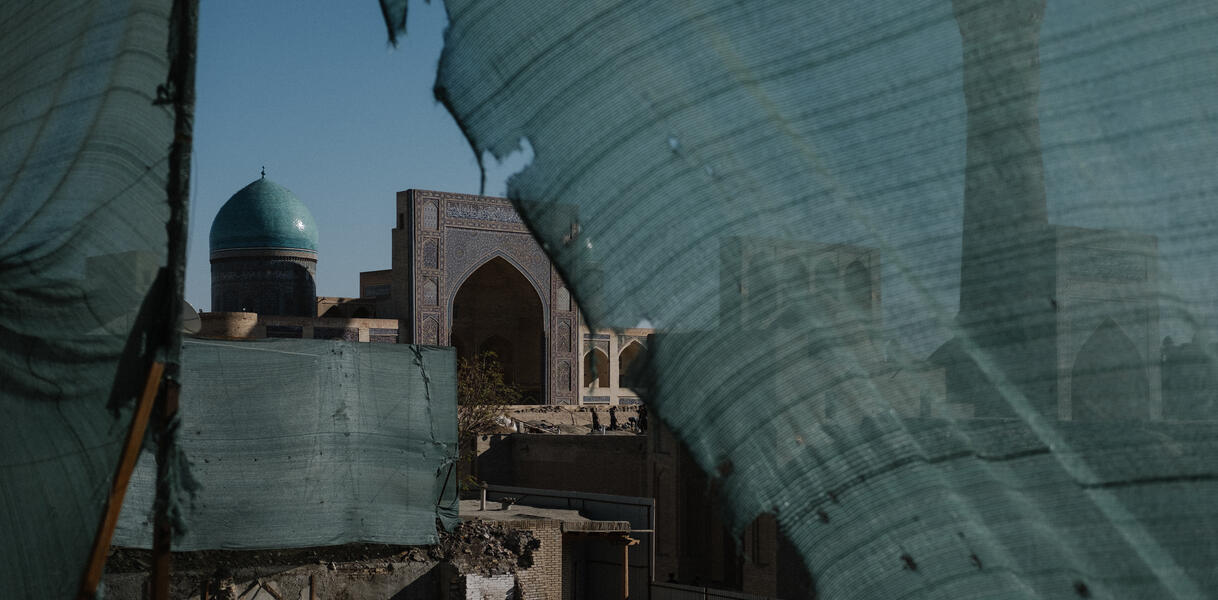 Blick auf eine Moschee, davor sieht man die Überreste eines Gebäudes. Ein grüner Sichtschutz grenzt die Baustelle ab