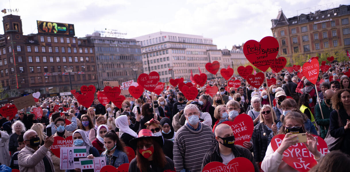 Demonstrierende Menschen halten rote Herzen in die Kamera
