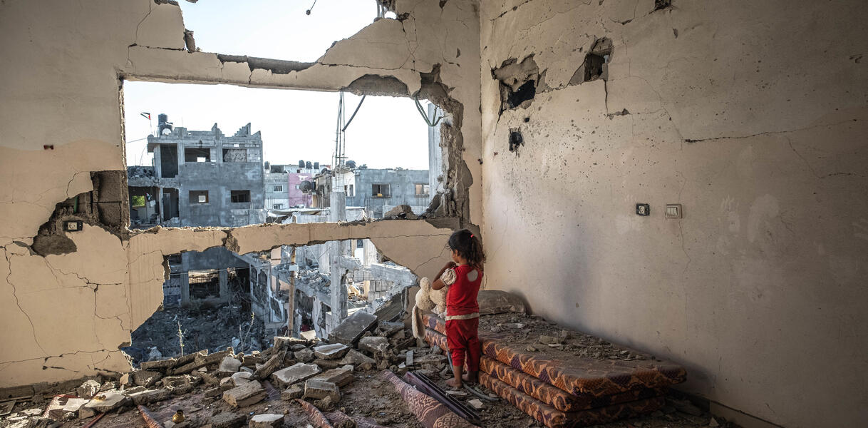 Ein kleines Mädchen steht in den Trümmern eines Gebäudes.