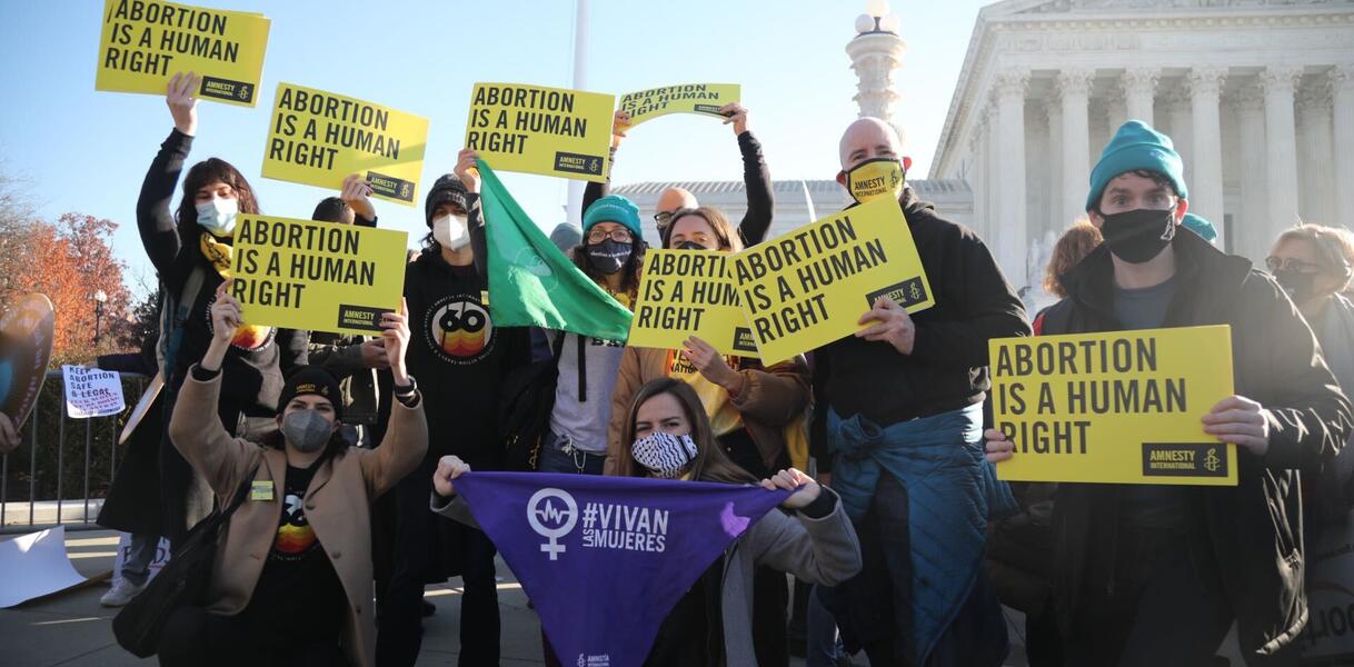 Das Foto zeigt eine circa zwölfköpfige Gruppe vor einem Gebäude. Sie halten mit dem Amnesty-Logo bedruckte Schilder hoch, auf denen steht: "Abortion is a human right". 