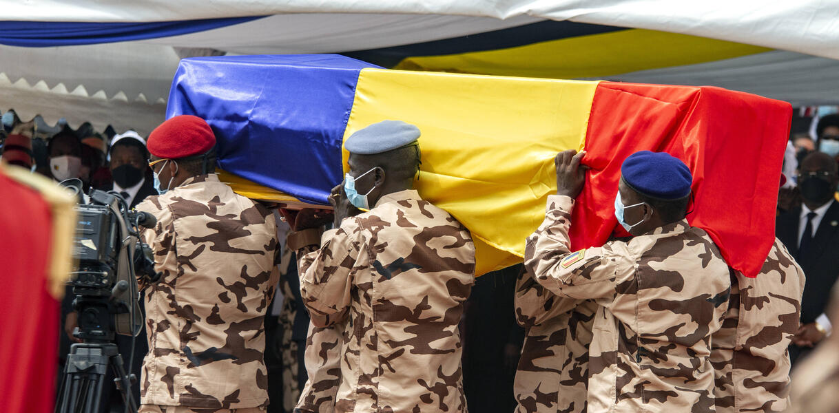 Sechs uniformierte Soldaten tragen einen Sarg, der mit der tschadischen Flagge umwickelt ist.