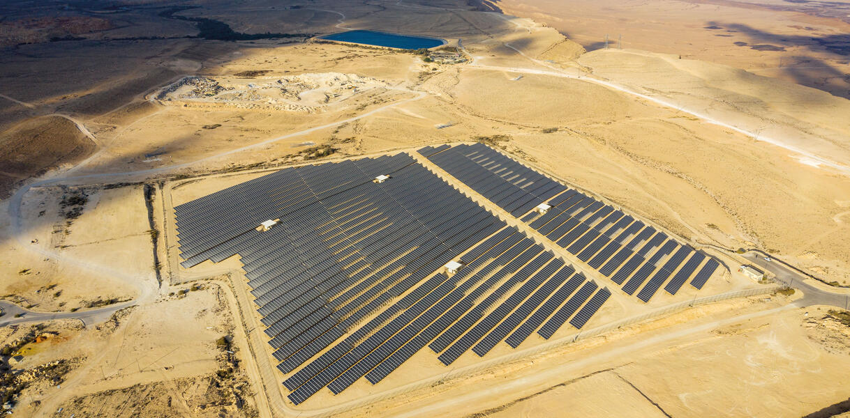 In einer Sandwüste sind in Reihen Sonnenkollektoren angelegt, eine Solarfam.
