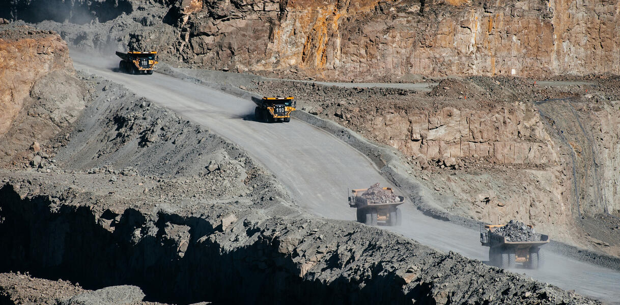 Lastwagen fahren auf einer Straße in einer staubigen Mine.