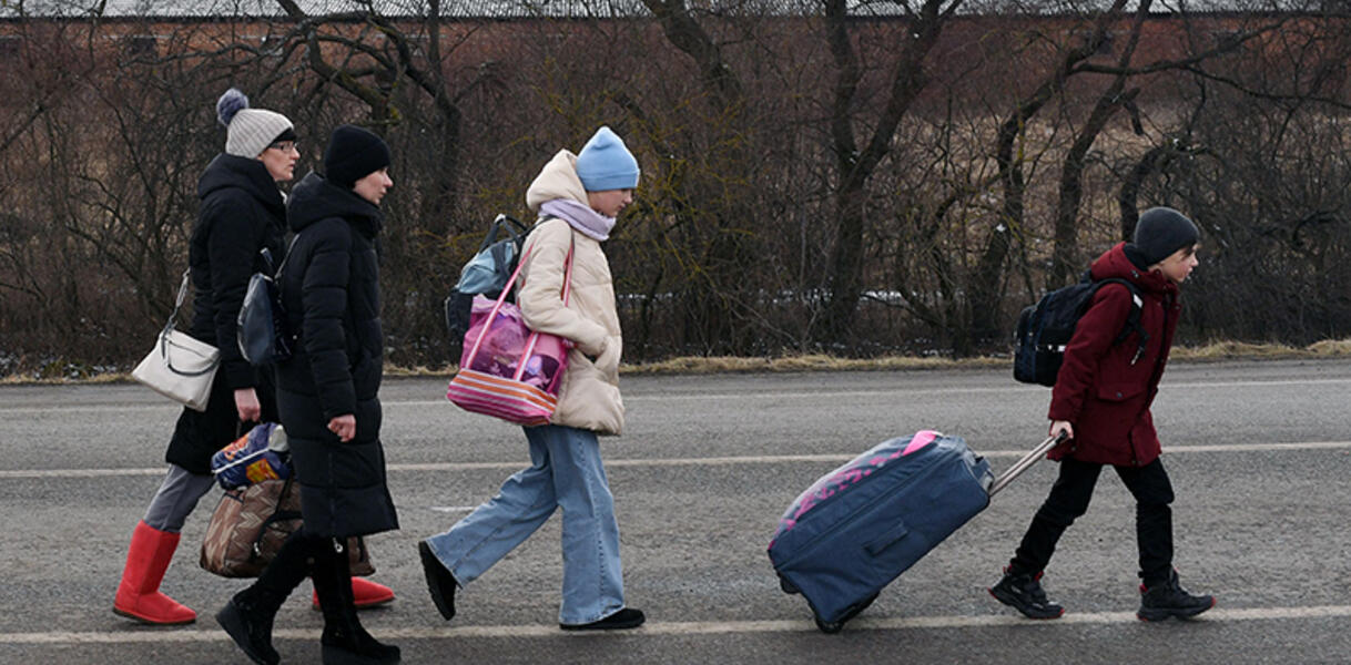 Das Bild zeigt Kinder und Frauen mit Koffern und Taschen