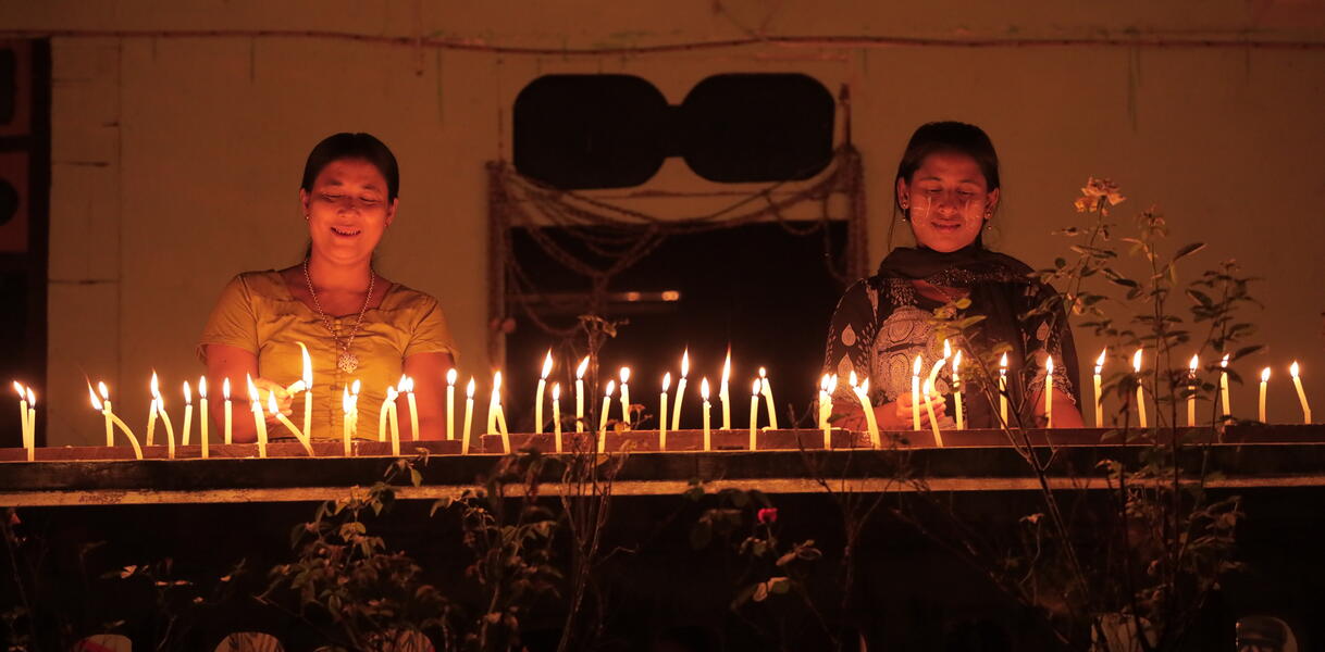 Das Bild zeigt zwei Frauen, die Kerzen anzünden