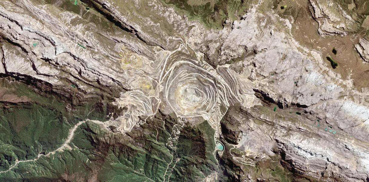 Vogelperspektive auf eine zerfurchte Landschaft, die durch den Tagebau einer Gold- und Kupfermine zerstört wurde.
