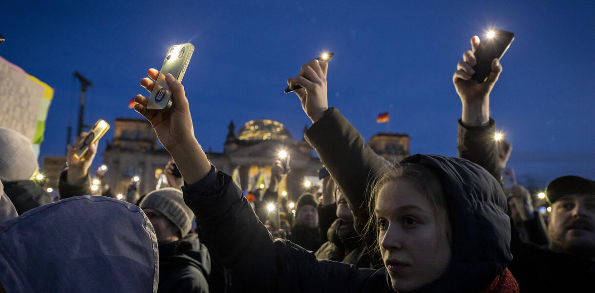 Das Bild zeigt Menschen, die protestieren. Sie halten ihre Handys in die Höhe