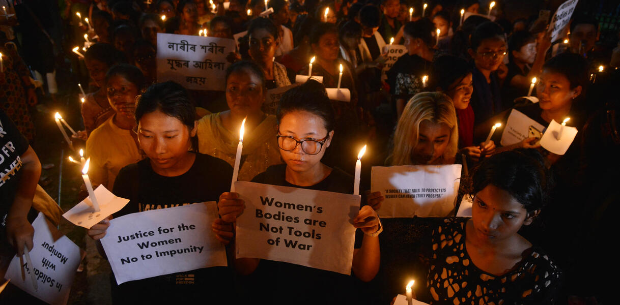 Frauen mit Kerzen halten Plakate hoch, auf denen Frauenrechte eingefordert werden.