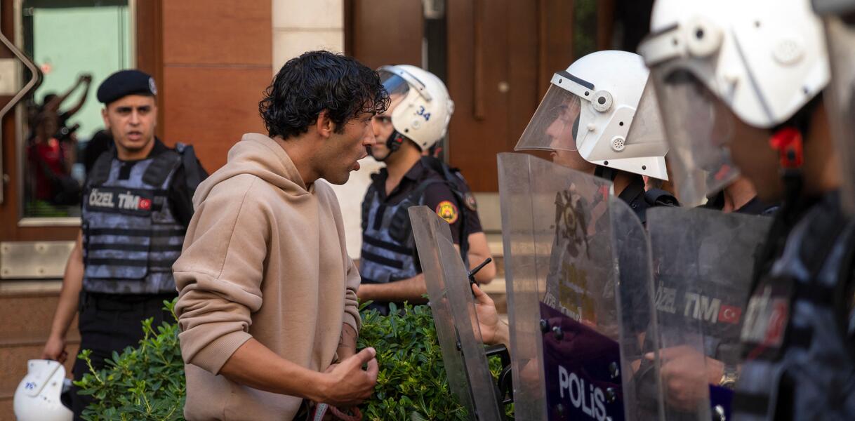 Ein Mann redet auf mit Helmen und Schutzschilden ausgestattete Polizisten ein.