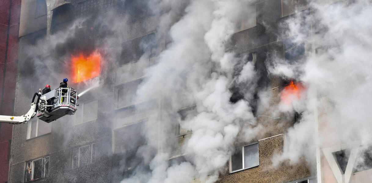 Ein Haus in Rauch eingehüllt, aus einigen Fenstern schlagen Flammen heraus.