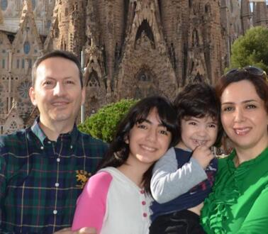 Ein Mann in einem kariertem Hemd posiert mit seinen zwei Kindern und Frau vor einer Kathedrale