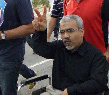 Das Bild zeigt einen Mann der in einem Rollstuhl sitzt und die Hand zum Victory-Zeichen hebt.