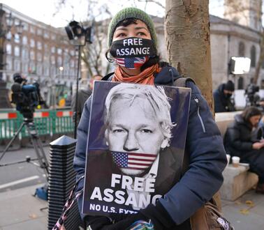Das Bild zeigt eine Frau, die bei einer Demonstration ein Bild von Julian Assange hält und der Forderung "Free Assange"