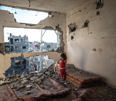 Ein kleines Mädchen steht in den Trümmern eines Gebäudes.