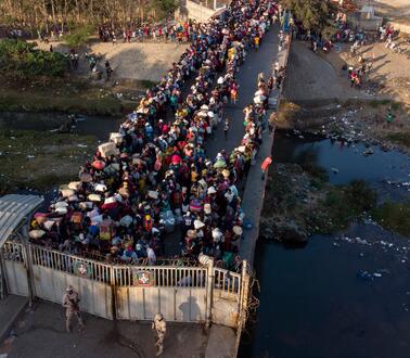 Auf einer Brücke steht eine Menschenmenge vor einer Absperrung.