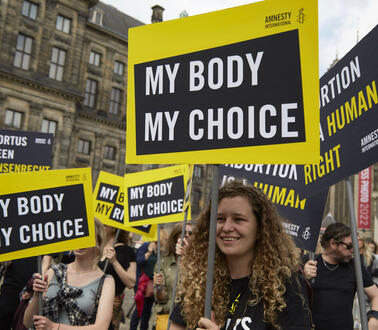 Das Bild zeigt mehrere Demonstrierende auf der Straße mit Schildern wie "My Body My Choice"