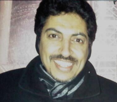 Porträtfoto von Abdulhadi Al-Khawaja, der eine Jacke und ein Schal trägt und die Kamera lächelt.