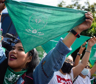 Frauen halten grüne Tücher in die Höhe mit dem spanischen Slogan für „Jugend im Widerstand“.
