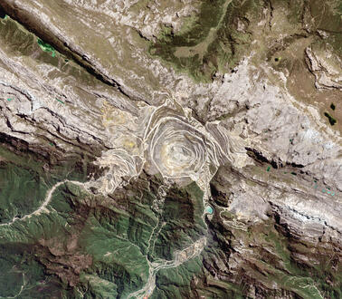 Vogelperspektive auf eine zerfurchte Landschaft, die durch den Tagebau einer Gold- und Kupfermine zerstört wurde.