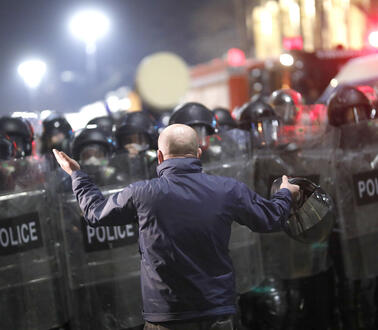Ein Mann mit erhobenen Armen vor einer Polizeikette
