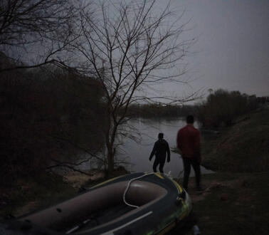 Menschen nachts an einem Flussufer mit einem Schlauchboot. 