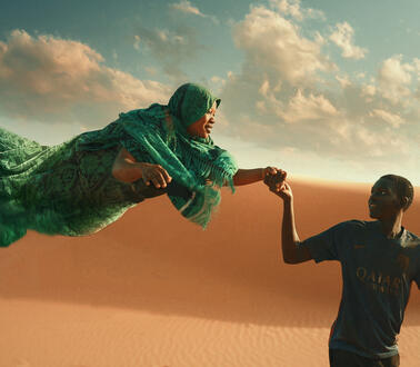 Das Bild zeigt einen jungen Mann, der eine Frau an der Hand hält, sie schwebt über dem Boden