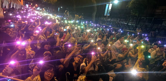Eine Protestgruppe steht mit bunten Lichtern in der Dunkelheit zusammen