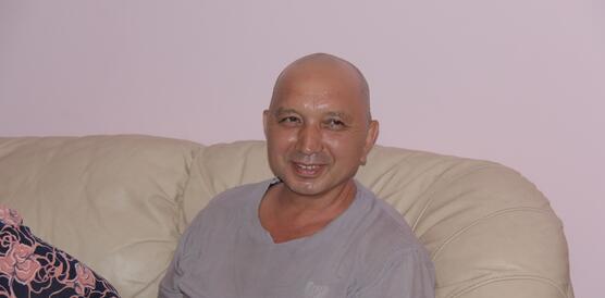 Erkin Musaev sitzt lächelnd auf einem Sofa