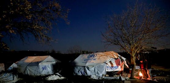 Zwei große Zelte der UNHCR im Dunkeln zwischen zwei Bäumen