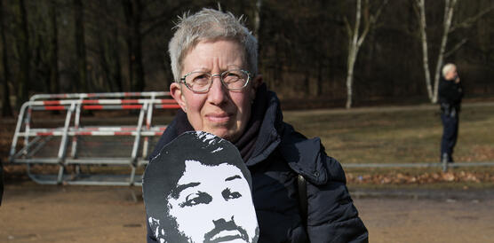 Eine Frau hält eine Taner-Kılıç-Maske aus Pappe und ein Schild mit der Aufschrift "Freiheit"