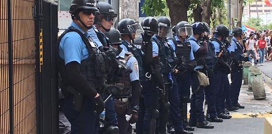 Polizist_innen aufgereiht, in Uniform und schwer bewaffnet