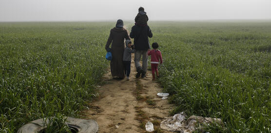 Eine Familie läuft auf einem Pfad durch einen grünen Acker
